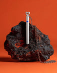 Elegant silver vibrator necklace resting on a stone surface, designed as a discreet bullet vibrator, mini vibrator, and stylish bullet sex toy for modern women