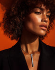 A woman with tan skin tone wearing an elegant vibrator necklace, designed as a discreet bullet vibrator, mini vibrator, and bullet sex toy for daily style and pleasure