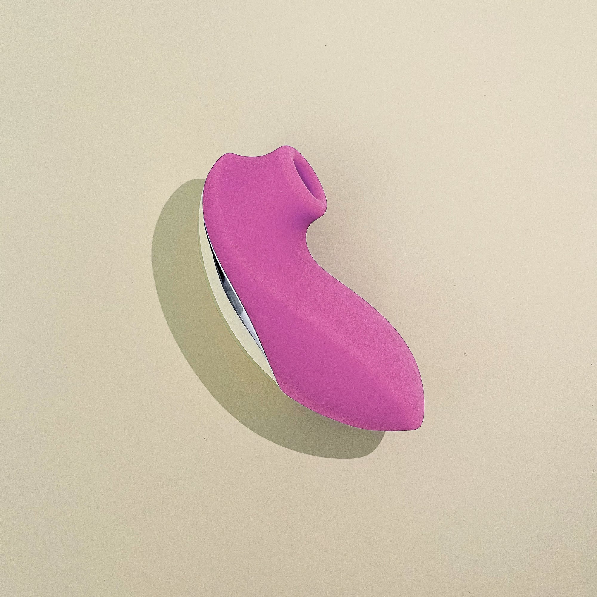 A pink clit stimulator placed on a flat surface